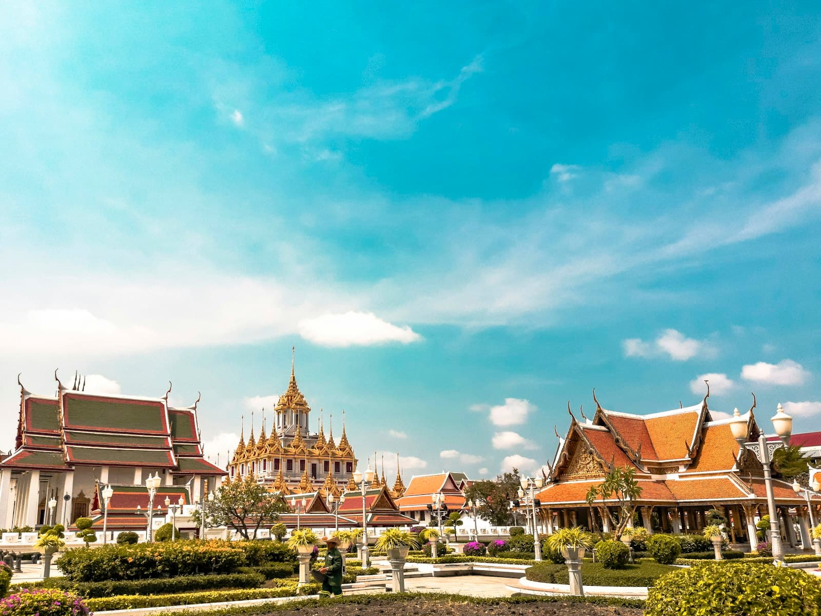 Ornate Thai temple roofs and a golden chedi in a formal garden