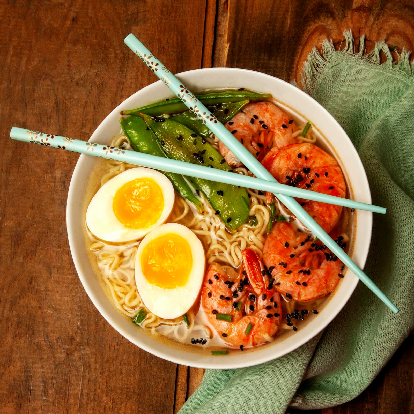 A bowl of noodle soup with shrimp, a halved egg, and vegetables
