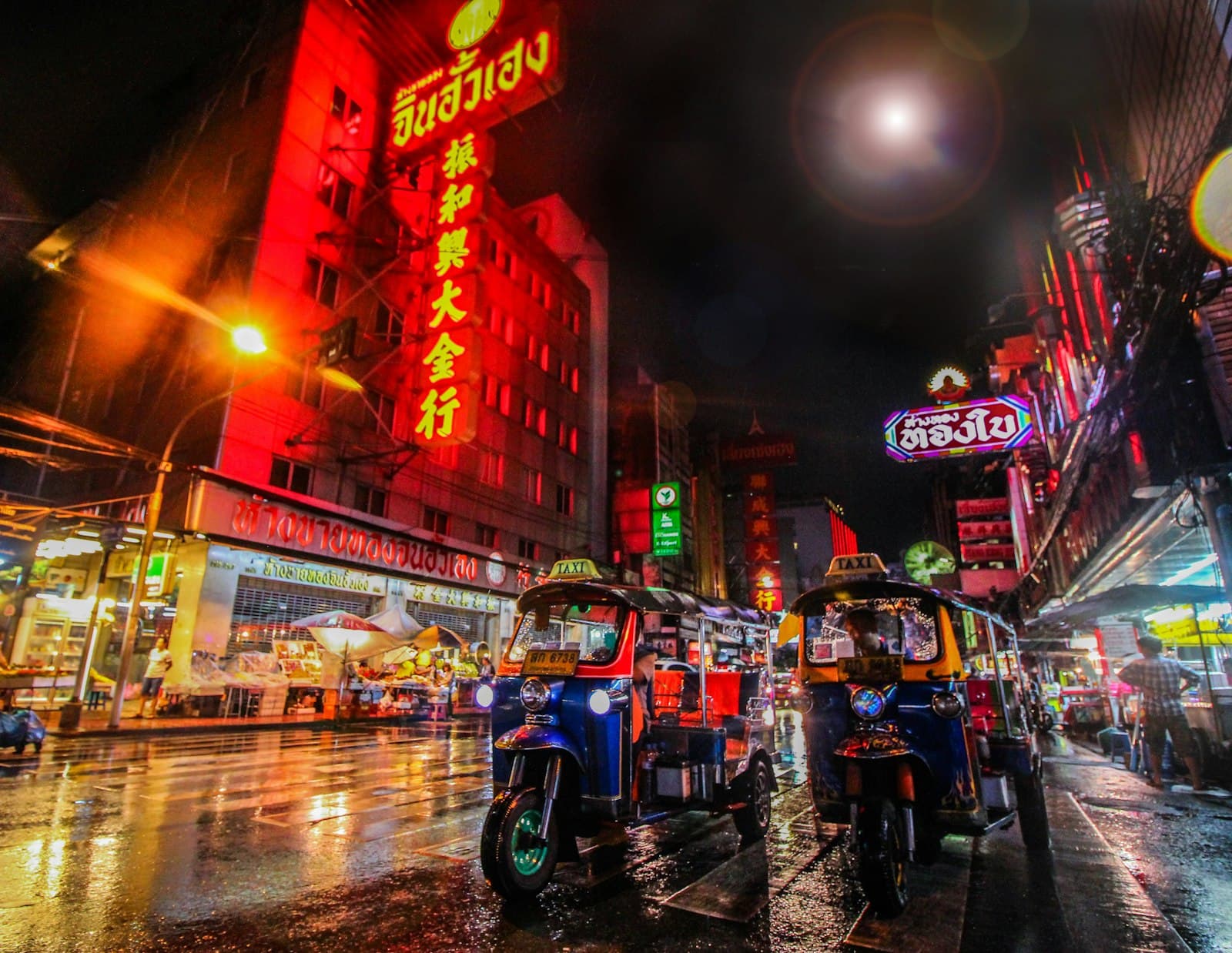 Tuk-tuks on a wet Bangkok street at night