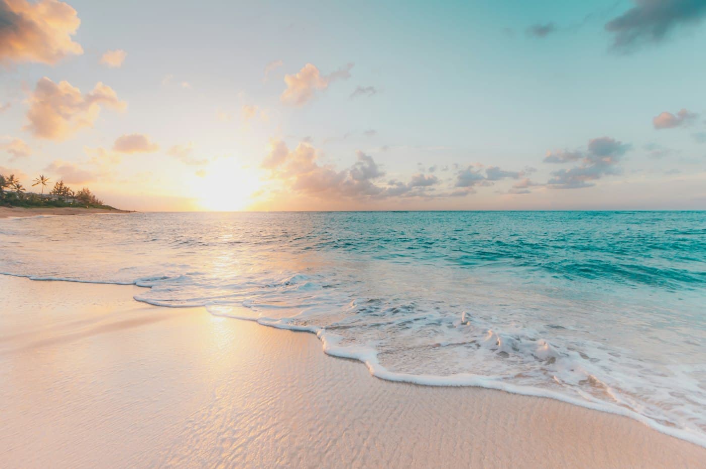 Sunrise over a sandy tropical beach with small waves