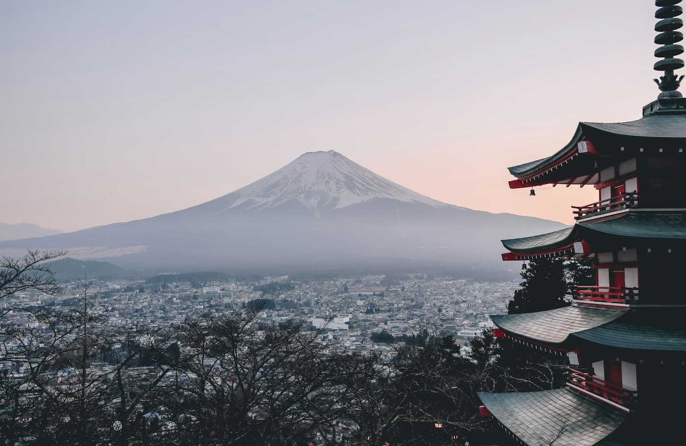 A pagoda in the foreground with Mount Fuji beyond a city