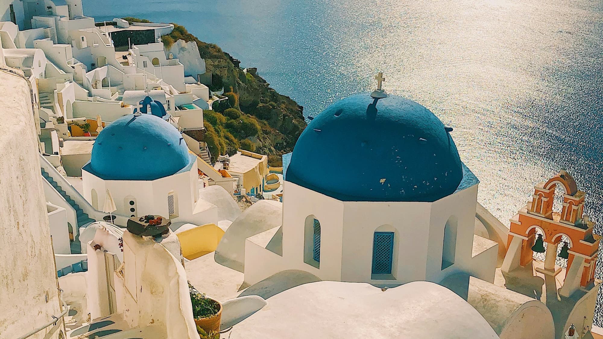 Whitewashed buildings and blue domes on a cliff above the sea in Santorini
