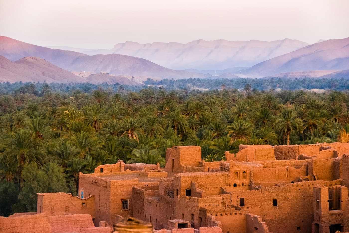 Earthen kasbah walls, palm groves, and desert mountains in Morocco